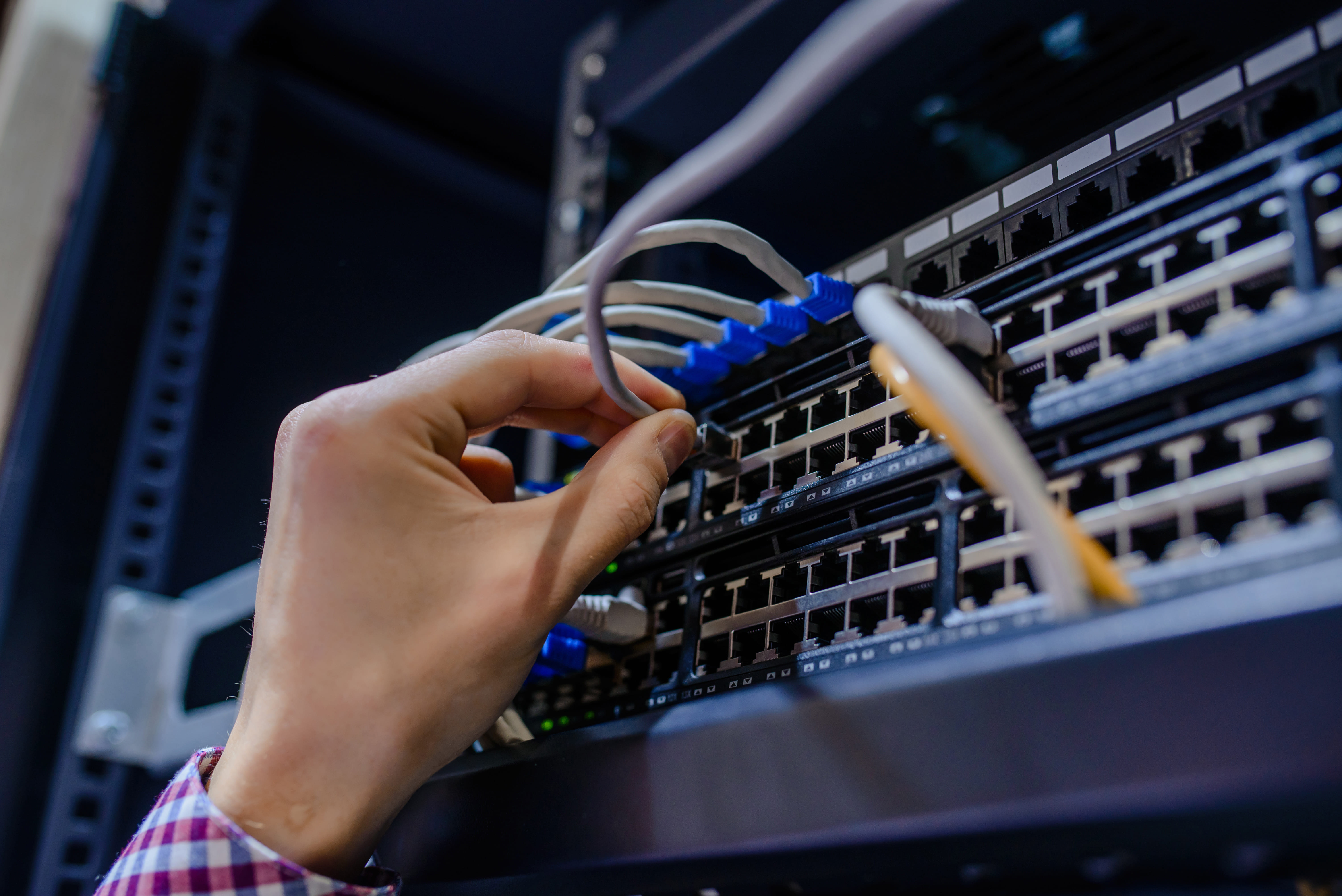 Engineer connecting network cables in rack infrastructure